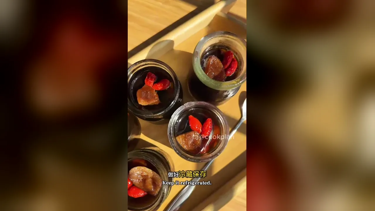 Tampak atas toples jeli sisik ikan jahe dan kurma merah berwarna amber pekat dengan goji, kurma, dan jahe